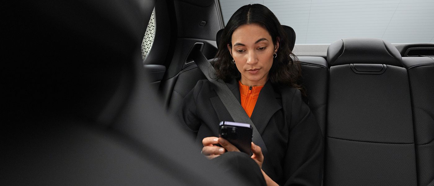 Eine Geschäftsfrau sitzt auf der RÜckbank einer Limousine