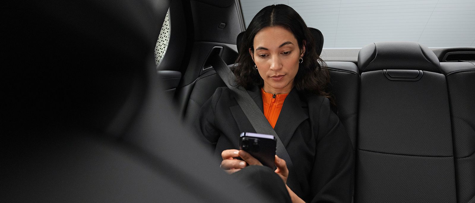 Geschäftsfrau sitzt im Auto und schaut ins Telefon